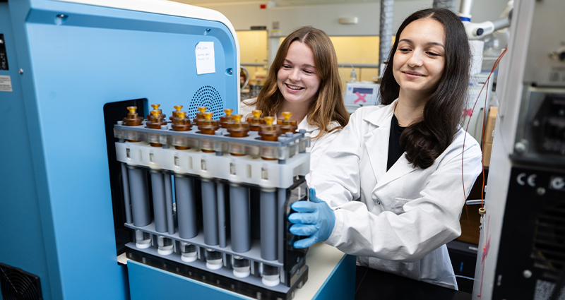 two female environmental science students working in lab on machine